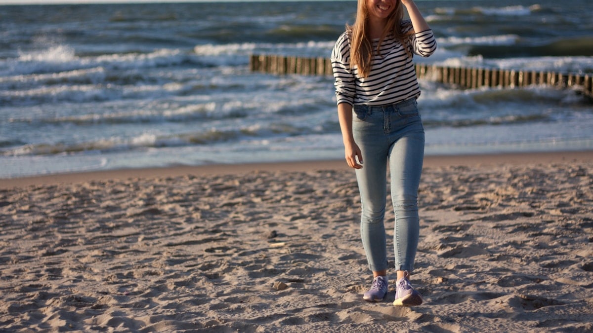a woman standing on top of a sandy beach